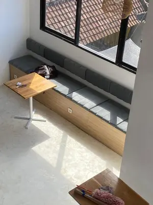 a bench in a room with a table and a window at WIJA's Bali Homestay in Legian