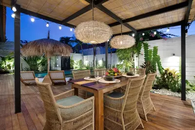 a patio with a wooden table and chairs and chandeliers at 3 Bedrooms Luxury Umalas with private pool in Kerobokan