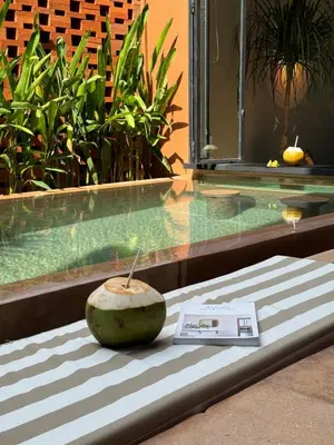 a coconut sitting on a bench next to a swimming pool at Kula Terra One Bedroom Villa in Kerobokan