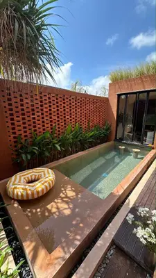 a swimming pool with a lounger in front of a house at Kula Terra One Bedroom Villa in Kerobokan
