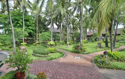 a garden with palm trees and a brick walkway at Sunset Suites, 1 bed apartment, Jayakarta hotel in Seminyak