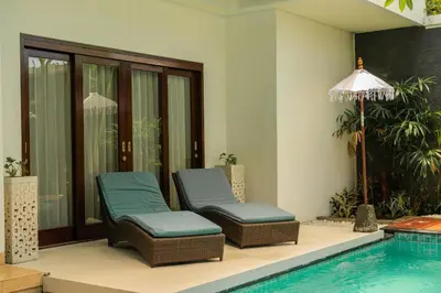 two chairs sitting next to a swimming pool at Bali Ula Villa in Nusa Dua