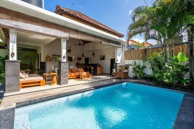 a swimming pool in front of a house at Kupu-Kupu Villa by iBali Management in Canggu