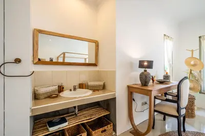 a bathroom with a sink and a desk with a mirror at Kupu-Kupu Villa by iBali Management in Canggu
