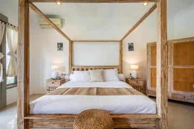 a bedroom with a large bed with a wooden frame at Kupu-Kupu Villa by iBali Management in Canggu