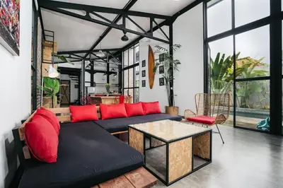 a living room with a black couch and red pillows at Villa Costa Plana - 2 bedroom industrial private villa in Umalas, between Canggu & Seminyak in Seminyak