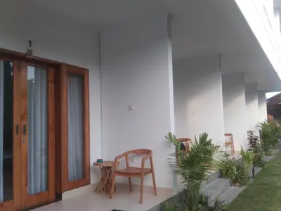 a room with a chair and a table and some plants at WJ Guest house in Kerobokan