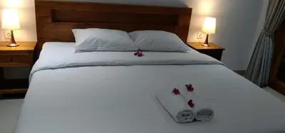 a white bed with two towels and two lamps at WJ Guest house in Kerobokan
