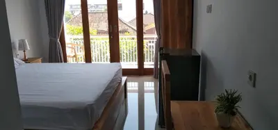 a bedroom with a white bed and a window at WJ Guest house in Kerobokan