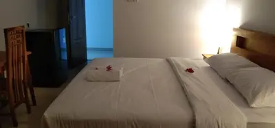 a bed with white sheets and red flowers on it at WJ Guest house in Kerobokan