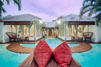 a villa with a swimming pool with red pillows on a wooden deck at Villa Laksmana 1 in Canggu