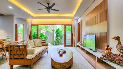 a living room with a couch and a tv at Casa De Gracia Sanur Beach by Nagisa Bali in Sanur