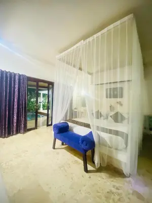 a bedroom with a canopy bed with a blue bench at Private Pool Classic Villa in Kuta