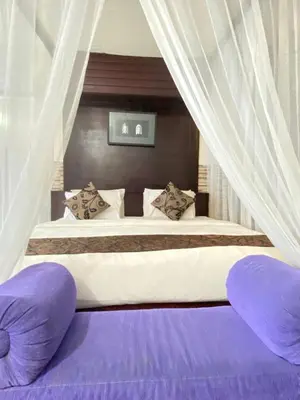 a bedroom with a large bed with purple pillows at Private Pool Classic Villa in Kuta