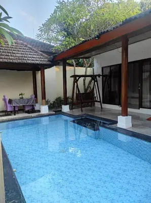a swimming pool in front of a house at Private Pool Classic Villa in Kuta