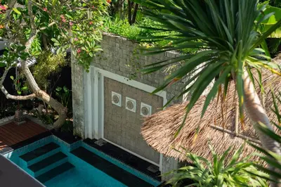 a swimming pool in a garden with a brick wall at Bali Stile villa in Nusa Dua