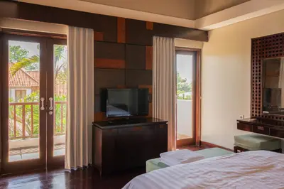 a bedroom with a bed and a tv and a balcony at Bali Stile villa in Nusa Dua