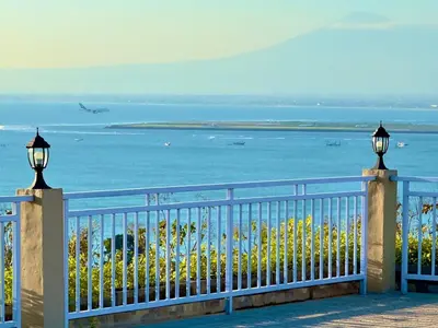 a fence with a view of the ocean and a plane at The Pandan Sari Hotel in Jimbaran