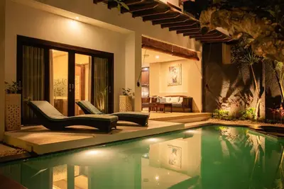 a swimming pool with two chairs and a house at Balinese stile villa in Nusa Dua