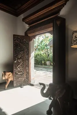 a dog is looking out of a door with an elephant at Segara Beach House Villa - Kuta in Kuta