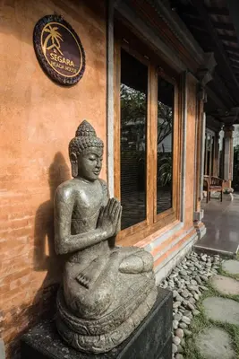 a statue in front of a building with a sign at Segara Beach House Villa - Kuta in Kuta