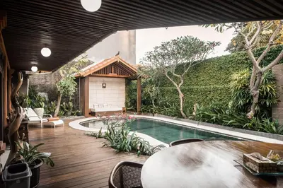 a pool in a backyard with a table and a building at Segara Beach House Villa - Kuta in Kuta