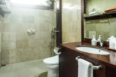 a bathroom with a sink and a toilet and a mirror at Segara Beach House Villa - Kuta in Kuta