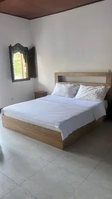 a bedroom with a large bed with white sheets and a window at Eimas Hive in Kerobokan