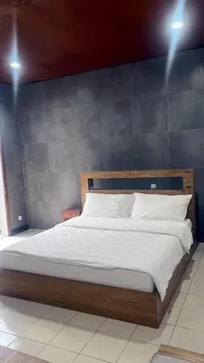 a bedroom with a large bed with a blue wall at Eimas Hive in Kerobokan