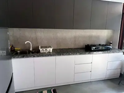 a kitchen counter with white cabinets and a sink at Eimas Hive in Kerobokan