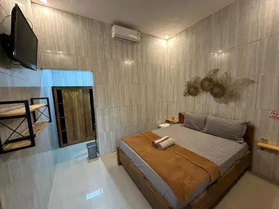 a bedroom with a bed and a flat screen tv at Kubu Alvian Guest House in Seminyak
