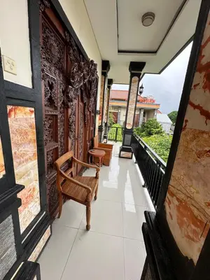 a balcony with chairs and a view of a building at Kubu Alvian Guest House in Seminyak