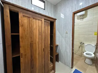 a bathroom with a toilet and a wooden door at Kubu Alvian Guest House in Seminyak