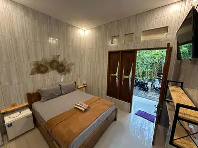 a bedroom with a bed and a television in it at Kubu Alvian Guest House in Seminyak