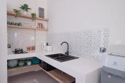 a white kitchen with a sink and a counter at Villa Dimaz in Seminyak