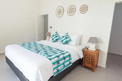 a bedroom with a large white bed and a night stand at Villa Dimaz in Seminyak