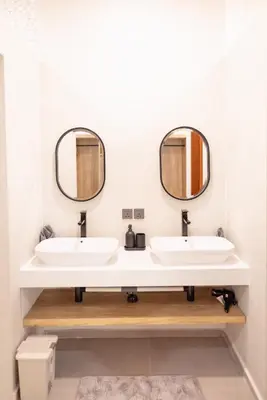 two sinks in a bathroom with two mirrors at Villa Dimaz in Seminyak
