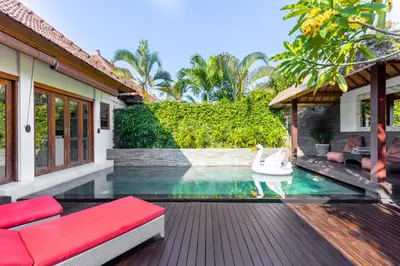 a house with a swimming pool with a red couch at Luxurious and Cozy King Beds, Pool, closed living room in Kuta