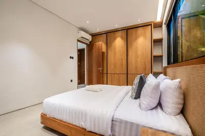 a bedroom with a bed with white sheets and pillows at Casa Tropicale Seminyak in Seminyak