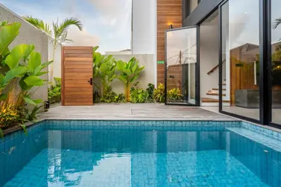 an infinity pool in a villa with a house at Casa Tropicale Seminyak in Seminyak