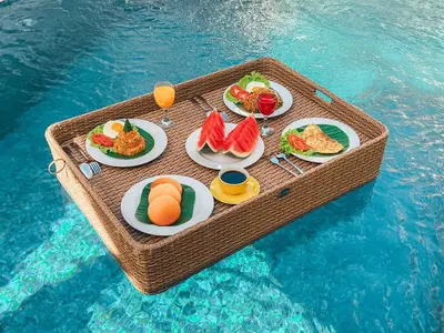 a picnic table with plates of food on top of the water at Villa Zanetta By Bali Asia Villa in Kerobokan