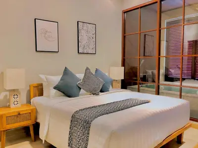 a bedroom with a large white bed with blue pillows at Putu Soemantri Four Persons Villas in Denpasar