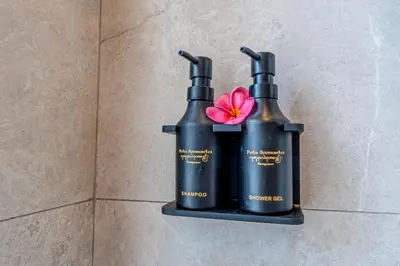 two black bottles on a shelf with a pink flower at Putu Soemantri Four Persons Villas in Denpasar