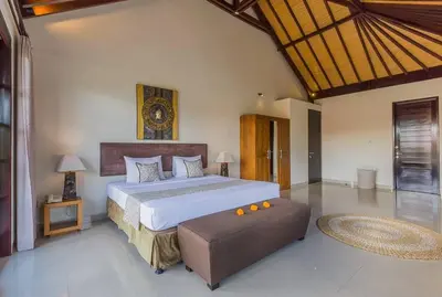 a bedroom with a large bed and a ottoman at Luxury Hideaway 4 Br Villa 5 minutes to the beach in Seminyak