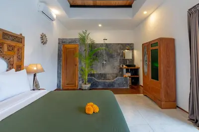 a bedroom with a bed and a bathroom with a tub at Villa Wamwui by DreamAwayBali in Seminyak