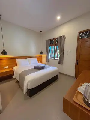 a bedroom with a large bed and a window at Kaman Bali Guesthouse in Seminyak