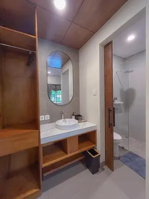a bathroom with a sink and a mirror and a toilet at Kaman Bali Guesthouse in Seminyak