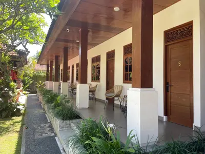 a porch of a house with chairs and a wooden door at Kaman Bali Guesthouse in Seminyak