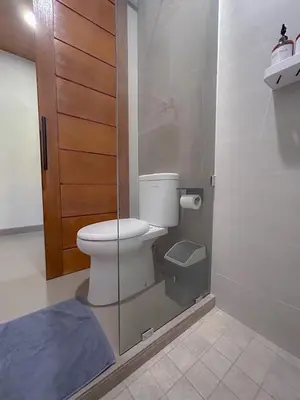 a bathroom with a toilet and a glass door at Kaman Bali Guesthouse in Seminyak