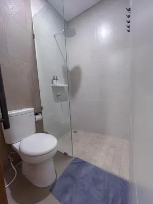 a bathroom with a toilet and a glass shower at Kaman Bali Guesthouse in Seminyak
